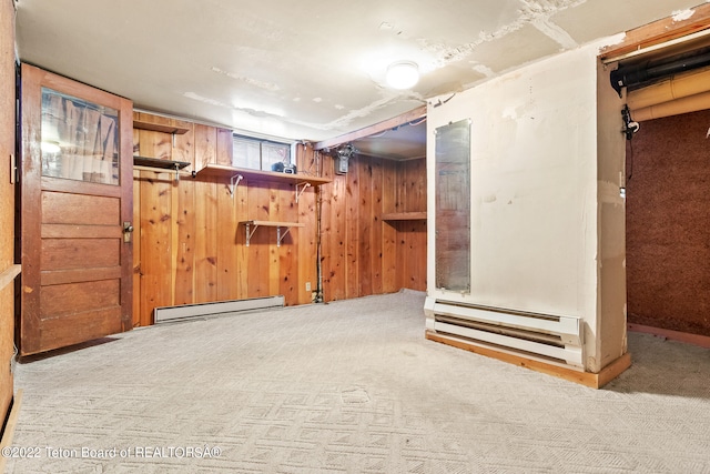 basement with wooden walls, a baseboard heating unit, and light colored carpet