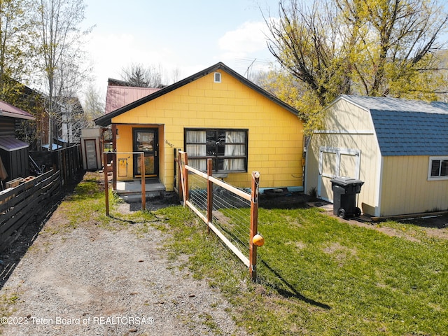 back of house featuring a storage shed and a lawn