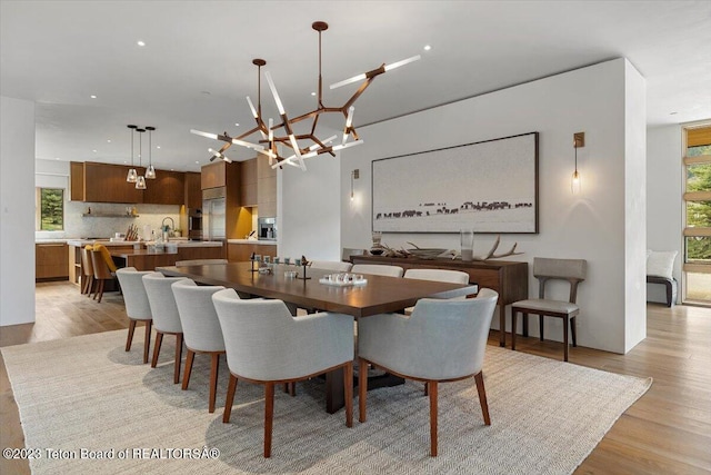 dining area featuring light hardwood / wood-style floors, sink, and an inviting chandelier