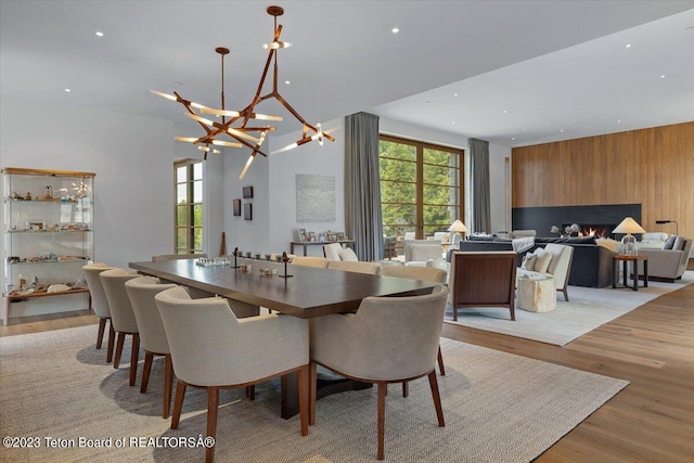 dining space with an inviting chandelier, wood walls, and light wood-type flooring