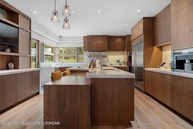 kitchen with light hardwood / wood-style flooring, an island with sink, and stainless steel appliances