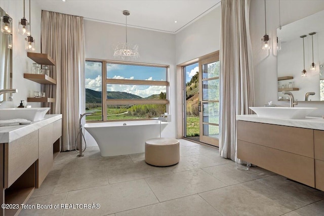 bathroom featuring a notable chandelier, vanity, tile flooring, and a healthy amount of sunlight