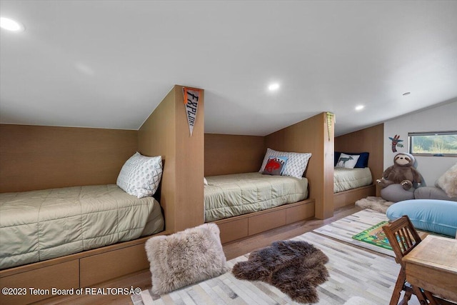 bedroom with light wood-type flooring and vaulted ceiling