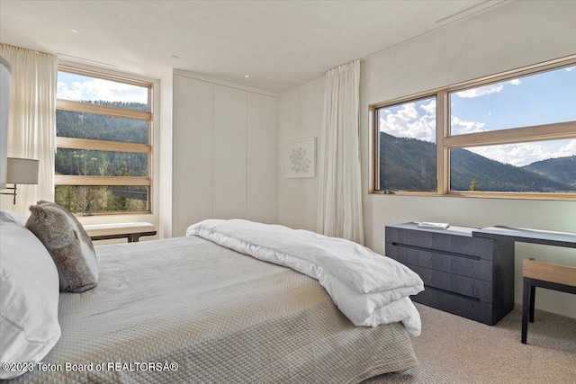 carpeted bedroom featuring a mountain view and multiple windows