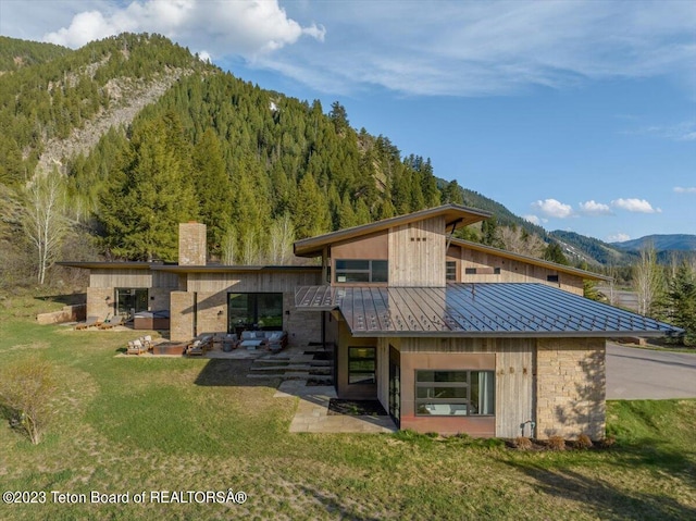 rear view of property featuring a patio area, a mountain view, and a yard