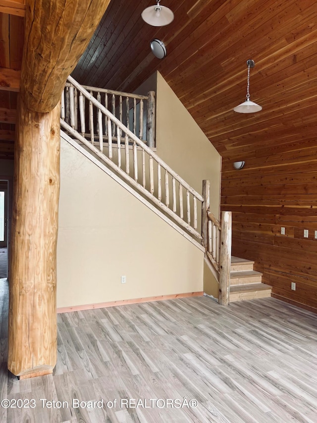 stairs with light hardwood / wood-style floors, wood walls, wooden ceiling, and high vaulted ceiling