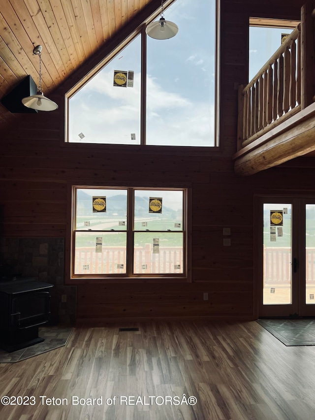 unfurnished living room with a wealth of natural light, dark wood-type flooring, and a wood stove