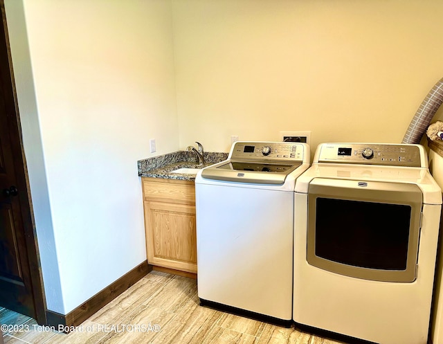 laundry area with cabinets, hookup for a washing machine, washer and clothes dryer, light wood-type flooring, and sink