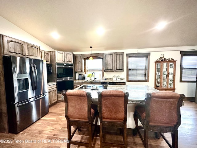 kitchen featuring a kitchen island, stainless steel fridge, double oven, and light hardwood / wood-style flooring