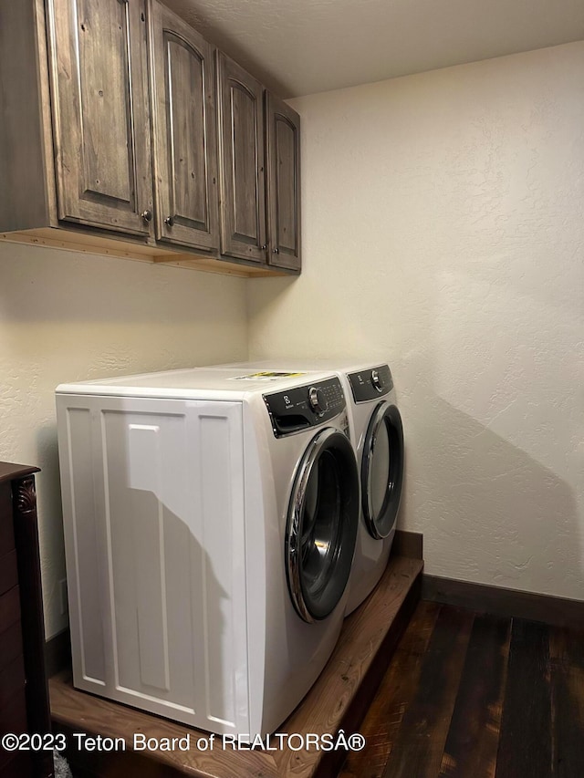 clothes washing area featuring dark hardwood / wood-style flooring, cabinets, and washing machine and dryer