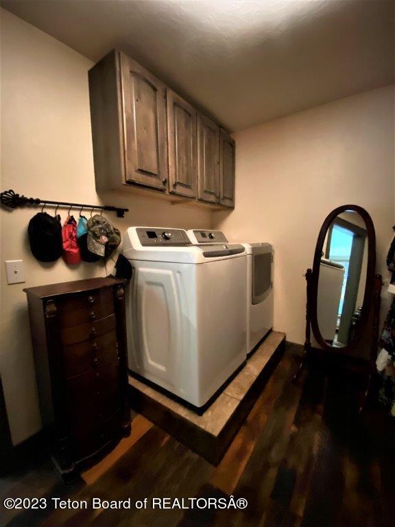 laundry room featuring separate washer and dryer, dark wood-type flooring, and cabinets