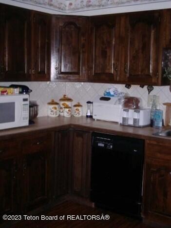 kitchen featuring dishwasher, dark brown cabinets, and backsplash