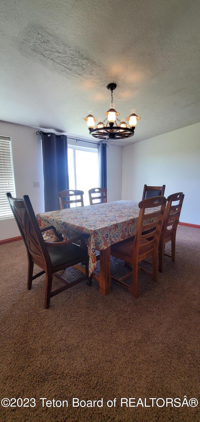 dining space featuring an inviting chandelier, a textured ceiling, and dark carpet