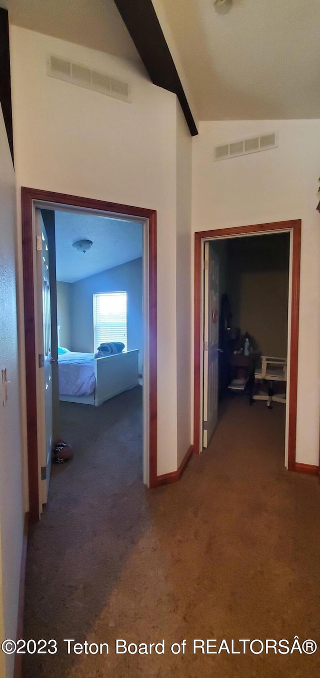 hallway featuring vaulted ceiling and dark carpet