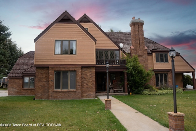 view of front facade with a balcony and a lawn