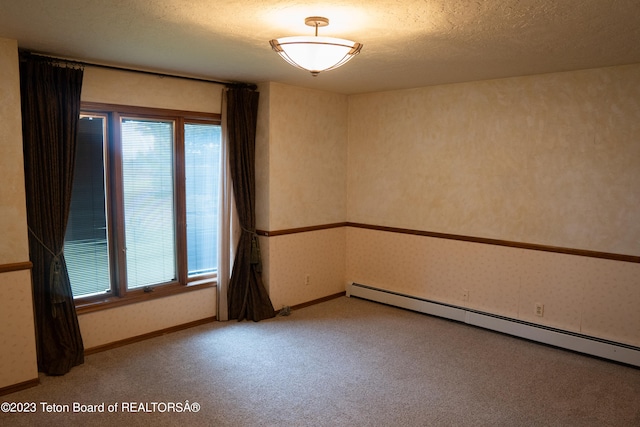 carpeted empty room featuring a baseboard heating unit, a textured ceiling, and a healthy amount of sunlight