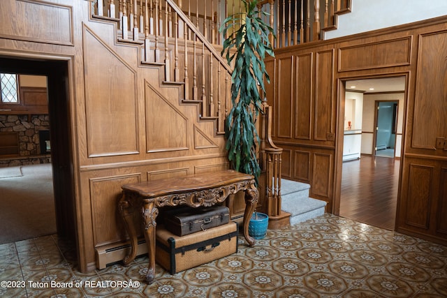 stairway featuring a towering ceiling, baseboard heating, and dark tile flooring