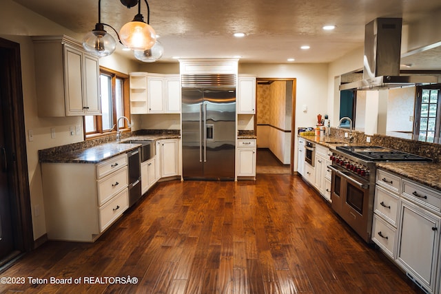 kitchen with dark hardwood / wood-style floors, island exhaust hood, hanging light fixtures, dark stone countertops, and high end appliances