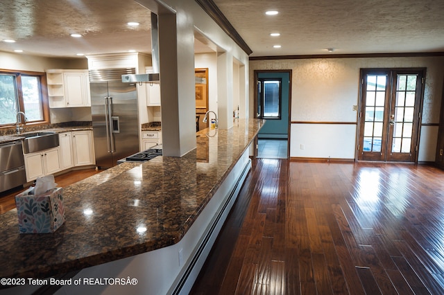 kitchen featuring french doors, appliances with stainless steel finishes, dark hardwood / wood-style flooring, dark stone countertops, and sink