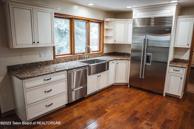 kitchen featuring dark stone countertops, sink, dark hardwood / wood-style flooring, and stainless steel appliances