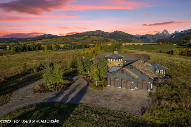 aerial view at dusk featuring a mountain view and a rural view