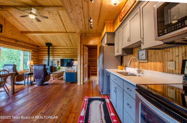 kitchen featuring log walls, sink, a wood stove, stove, and wood-type flooring