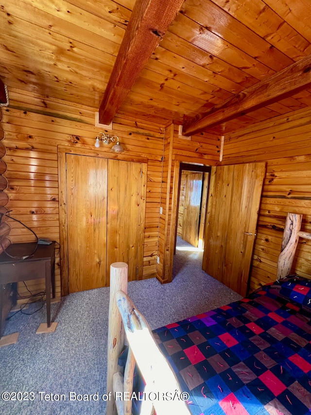 bedroom with wooden walls, dark colored carpet, beamed ceiling, and wooden ceiling