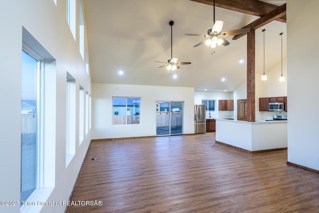 unfurnished living room featuring high vaulted ceiling, ceiling fan, a wealth of natural light, and dark hardwood / wood-style flooring