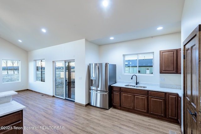 kitchen with light wood-type flooring, stainless steel fridge, a wealth of natural light, and sink