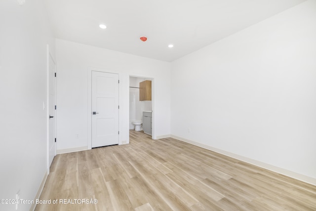 unfurnished bedroom with light wood-type flooring and ensuite bathroom