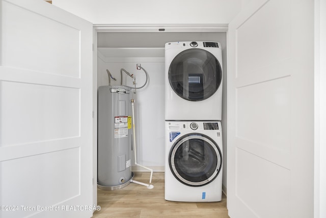 clothes washing area featuring water heater, stacked washer and dryer, and light hardwood / wood-style flooring