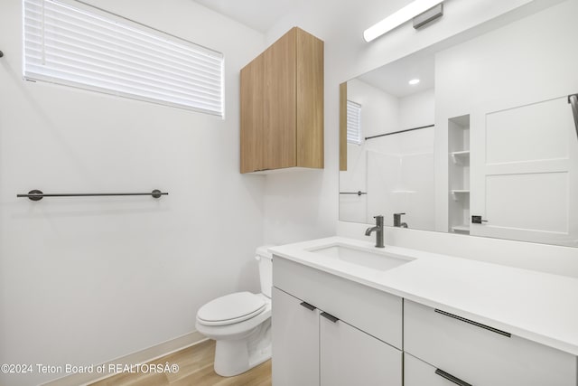 bathroom featuring walk in shower, vanity, hardwood / wood-style flooring, and toilet