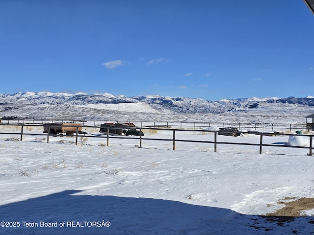 yard layered in snow featuring a rural view, a mountain view, and fence