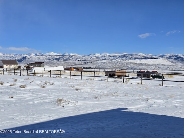 yard layered in snow with fence, a mountain view, and a rural view