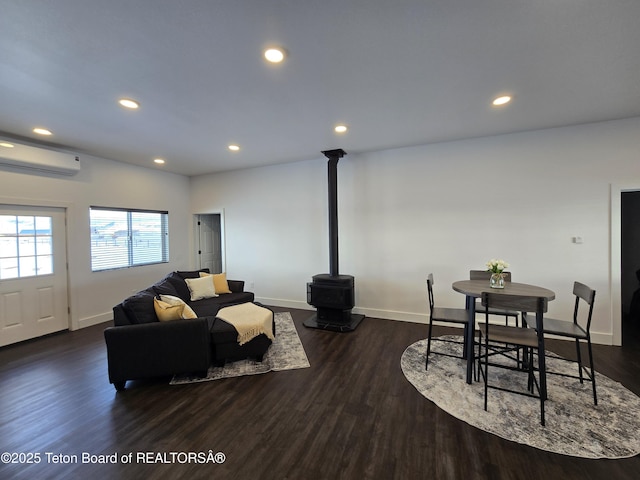 living area featuring dark wood-style flooring, a wall mounted AC, a wood stove, and recessed lighting