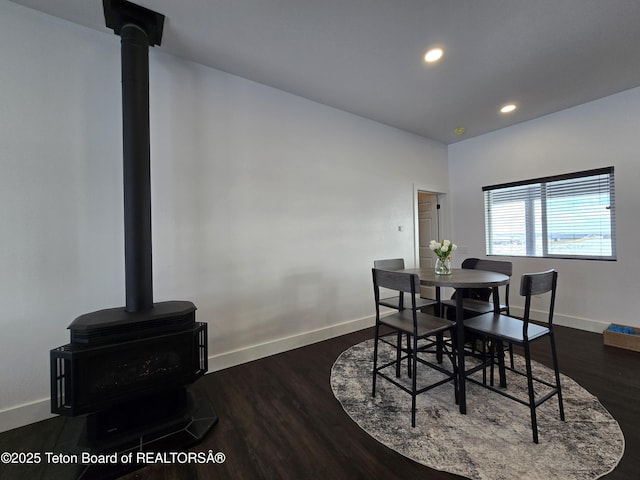 dining space with recessed lighting, dark wood finished floors, a wood stove, and baseboards