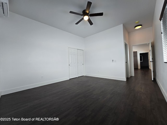 unfurnished bedroom with dark wood-style floors, a closet, baseboards, and a ceiling fan