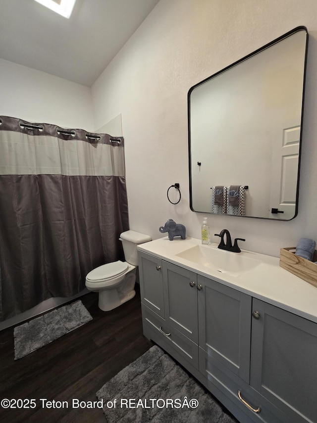 bathroom with toilet, wood finished floors, vanity, and a shower with curtain