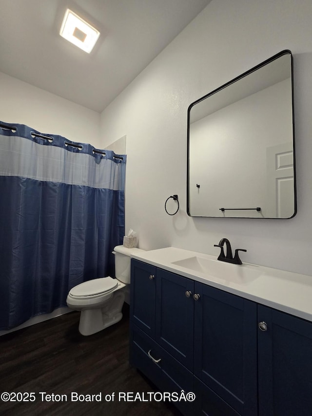 full bath with curtained shower, vanity, toilet, and wood finished floors