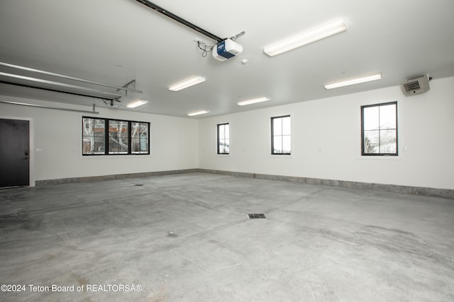 garage featuring a wall mounted AC and a garage door opener