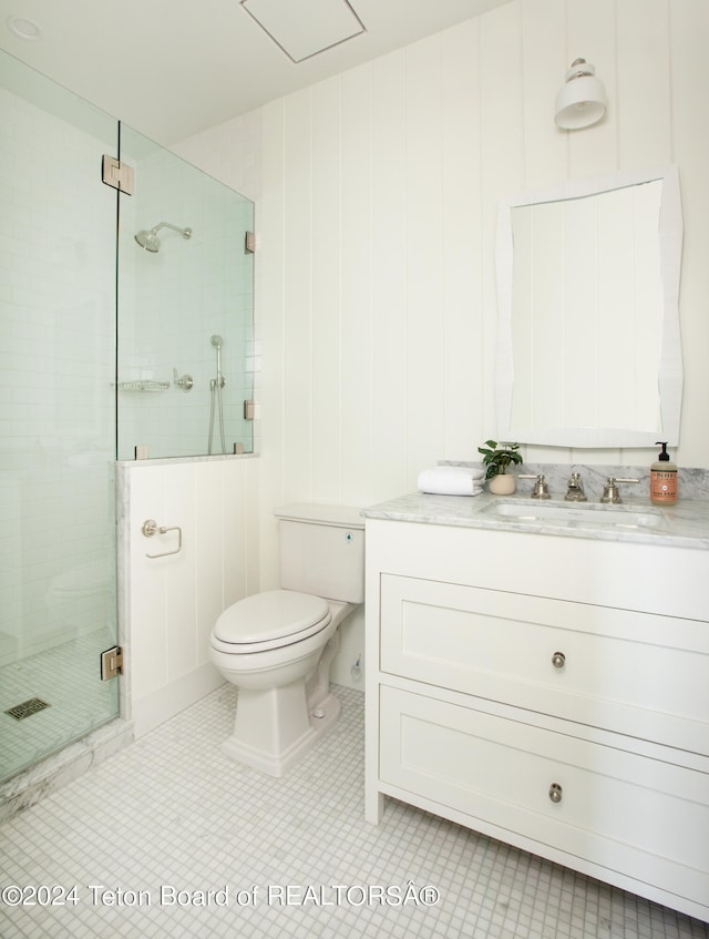 bathroom with vanity with extensive cabinet space, toilet, tile flooring, and walk in shower