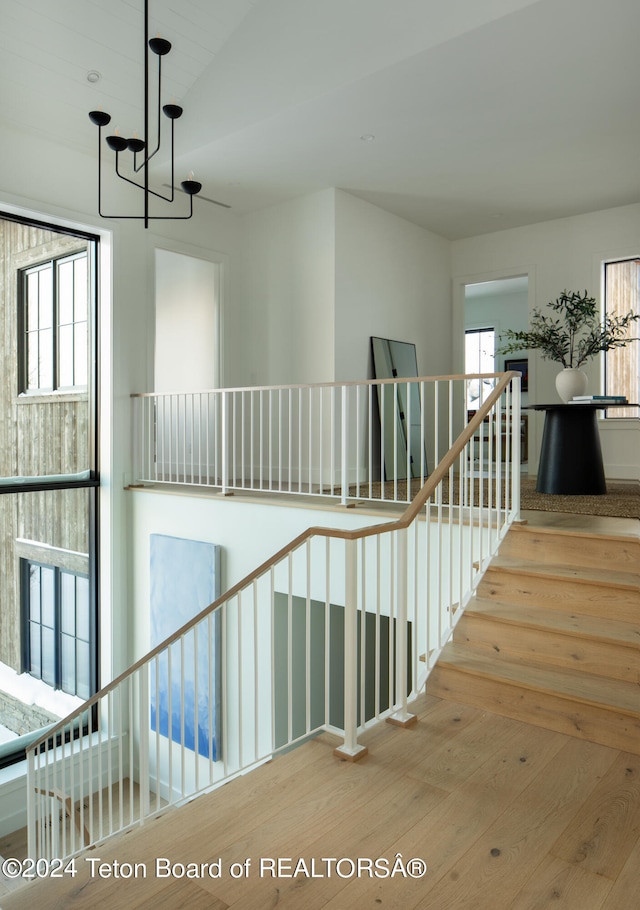 stairs featuring hardwood / wood-style flooring and a notable chandelier