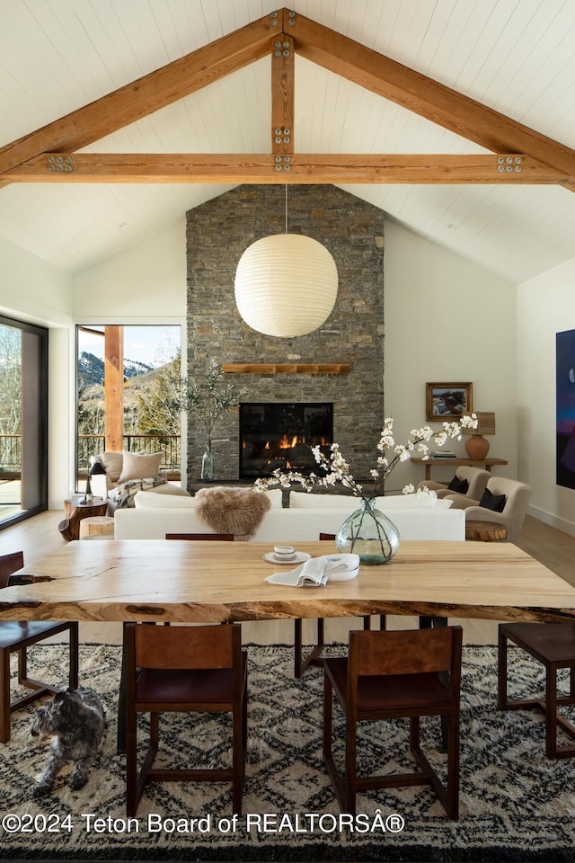 dining room featuring beamed ceiling, high vaulted ceiling, and a fireplace