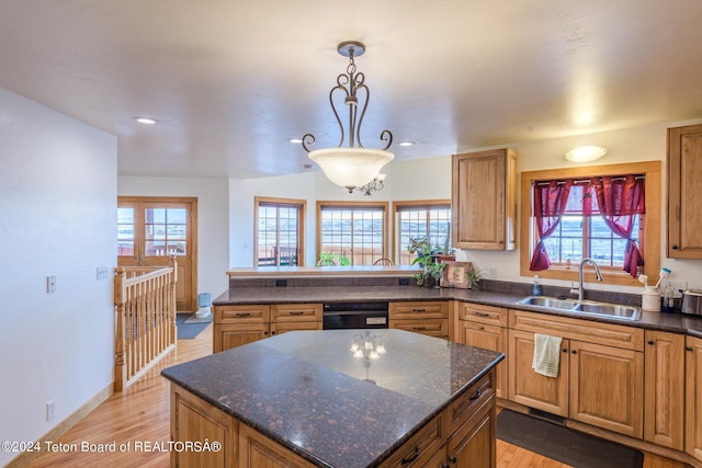 kitchen featuring dark stone counters, decorative light fixtures, light hardwood / wood-style floors, and sink