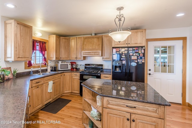 kitchen featuring pendant lighting, sink, black appliances, light hardwood / wood-style floors, and custom range hood