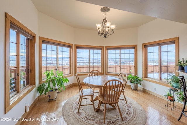 dining room with a water view, an inviting chandelier, and light wood-type flooring