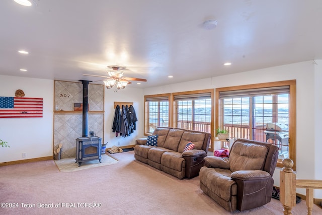 living room with carpet floors, a wood stove, a wealth of natural light, and ceiling fan