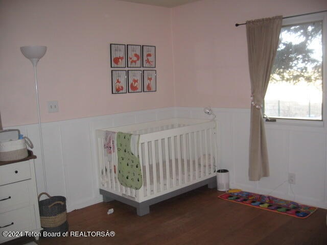 unfurnished bedroom featuring a nursery area and dark hardwood / wood-style flooring