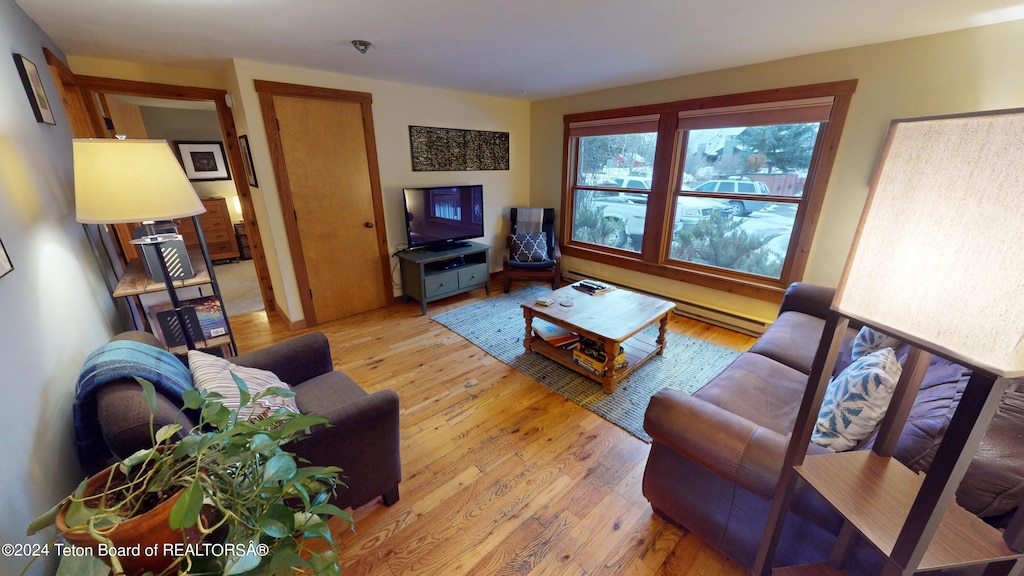 living room with a baseboard heating unit and light hardwood / wood-style floors