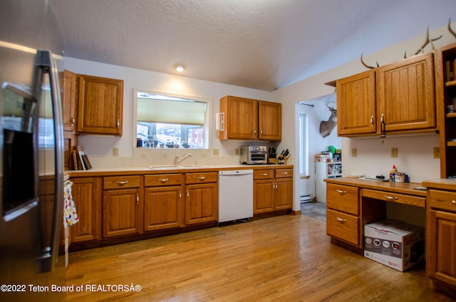 kitchen featuring light hardwood / wood-style floors, stainless steel fridge, dishwasher, a textured ceiling, and sink